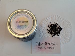 Jar of elder berry syrup and dried elder berries lying beside it