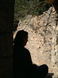 A silhouette  of a sad woman sitting in a dark cave.