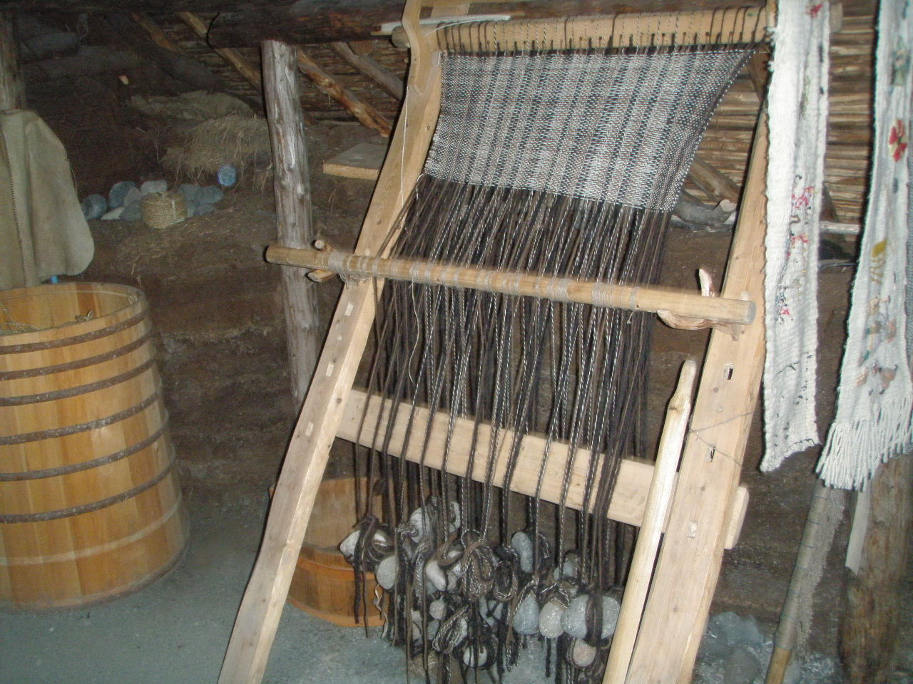 A Viking settlement loom A loom with fabric being woven and the warp threads are weighted down with stones.
