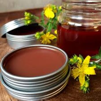 Red coloured St. John's Wort Salve with the yellow flowers of St. John's wort and a red infused jar of oil. 