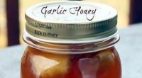 A glass jar filled with honey and garlic cloves.